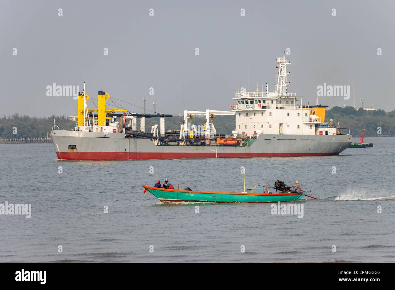 Ein Fischerboot segelt auf dem Chao Phraya River, ein Baggerboot im Hintergrund, Thailand Stockfoto