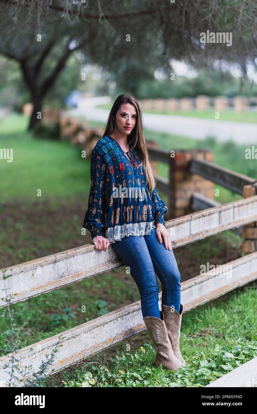 Eine weiße Frau Mitte zwanzig lehnte sich gegen einen Holzzaun und starrte in die Kamera. Stockfoto