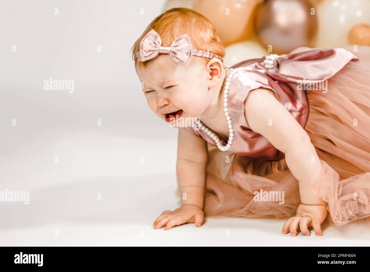 Das kleine weinende, unglückliche rothaarige Baby-Mädchen feiert den ersten Geburtstag. 1 Jahre Familienparty professionelles Fotoshooting im Fotostudio. Süße adora Stockfoto