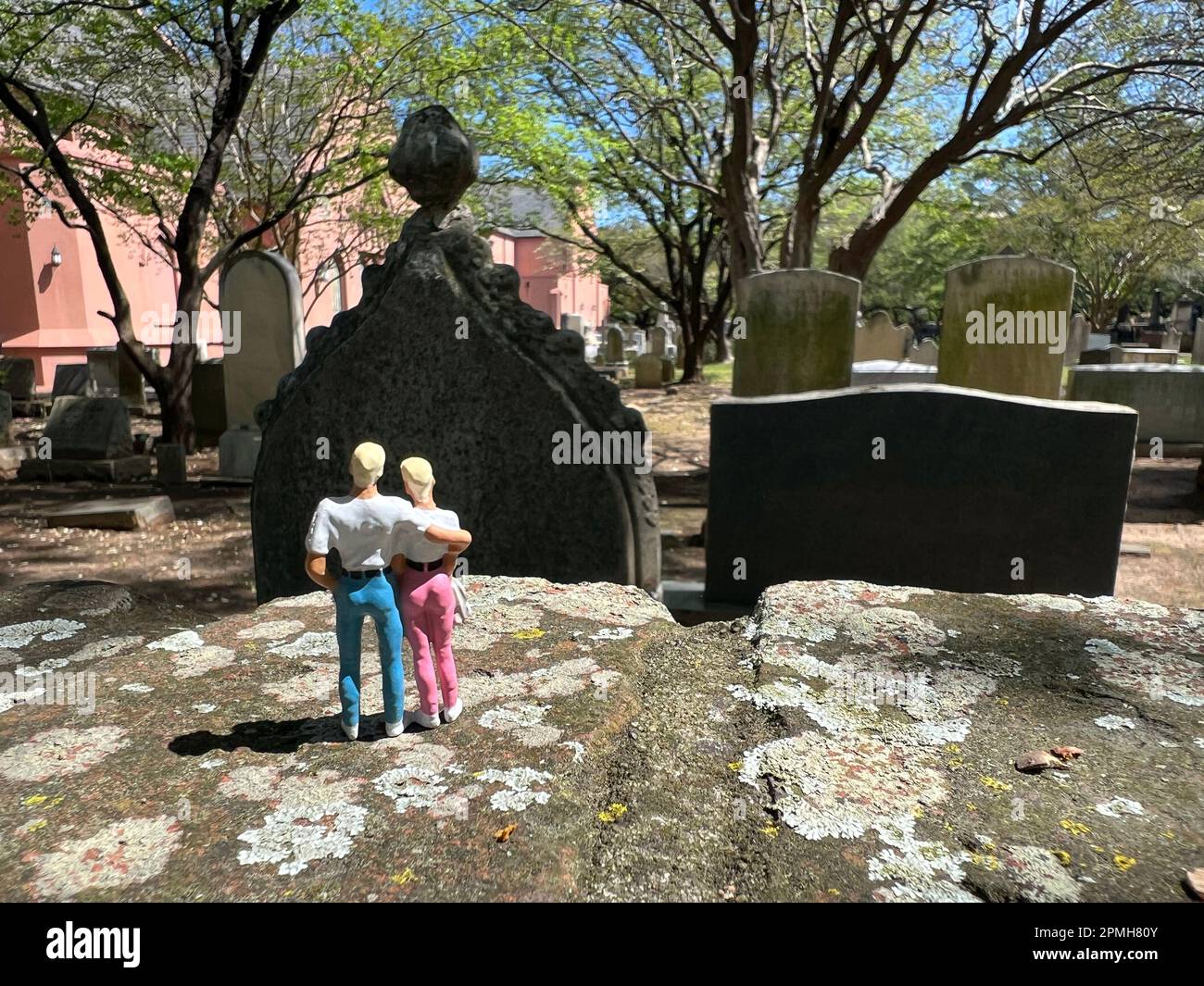 Ein blondes Paar Miniaturmenschen besucht den Friedhof. Das Konzept von Tod und Verlust und die Zukunft. Stockfoto