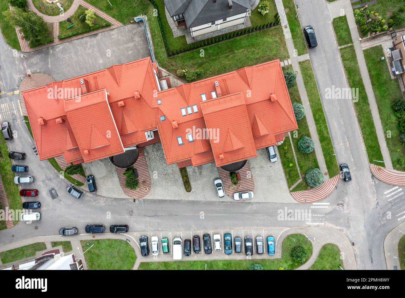 Modernes Wohnhaus mit rotem Ziegeldach und Straße mit geparkten Autos. Vorort-Viertel am Sommertag. Draufsicht. Stockfoto