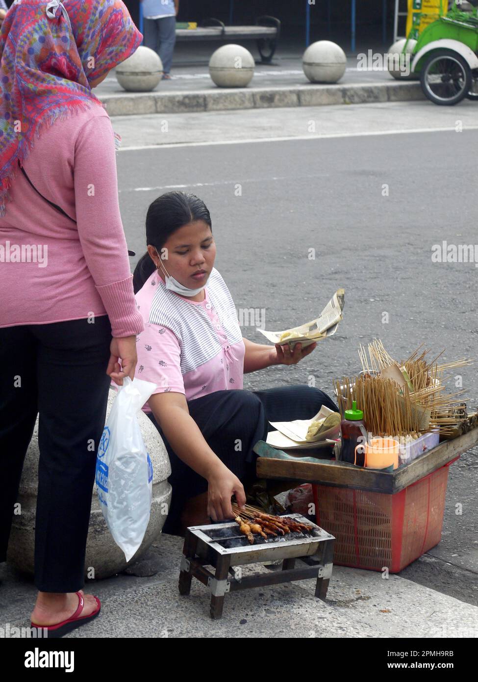 Ein ehrliches Foto von einer Frau, die Satay am Straßenrand in Indonesien verkauft Stockfoto