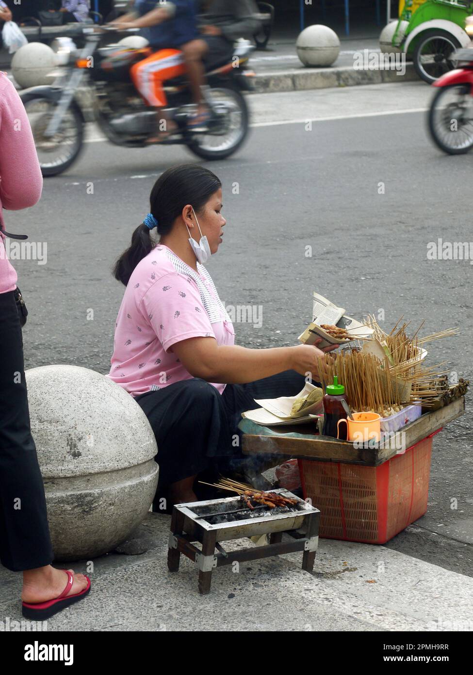 Ein ehrliches Foto von einer Frau, die Satay am Straßenrand in Indonesien verkauft Stockfoto
