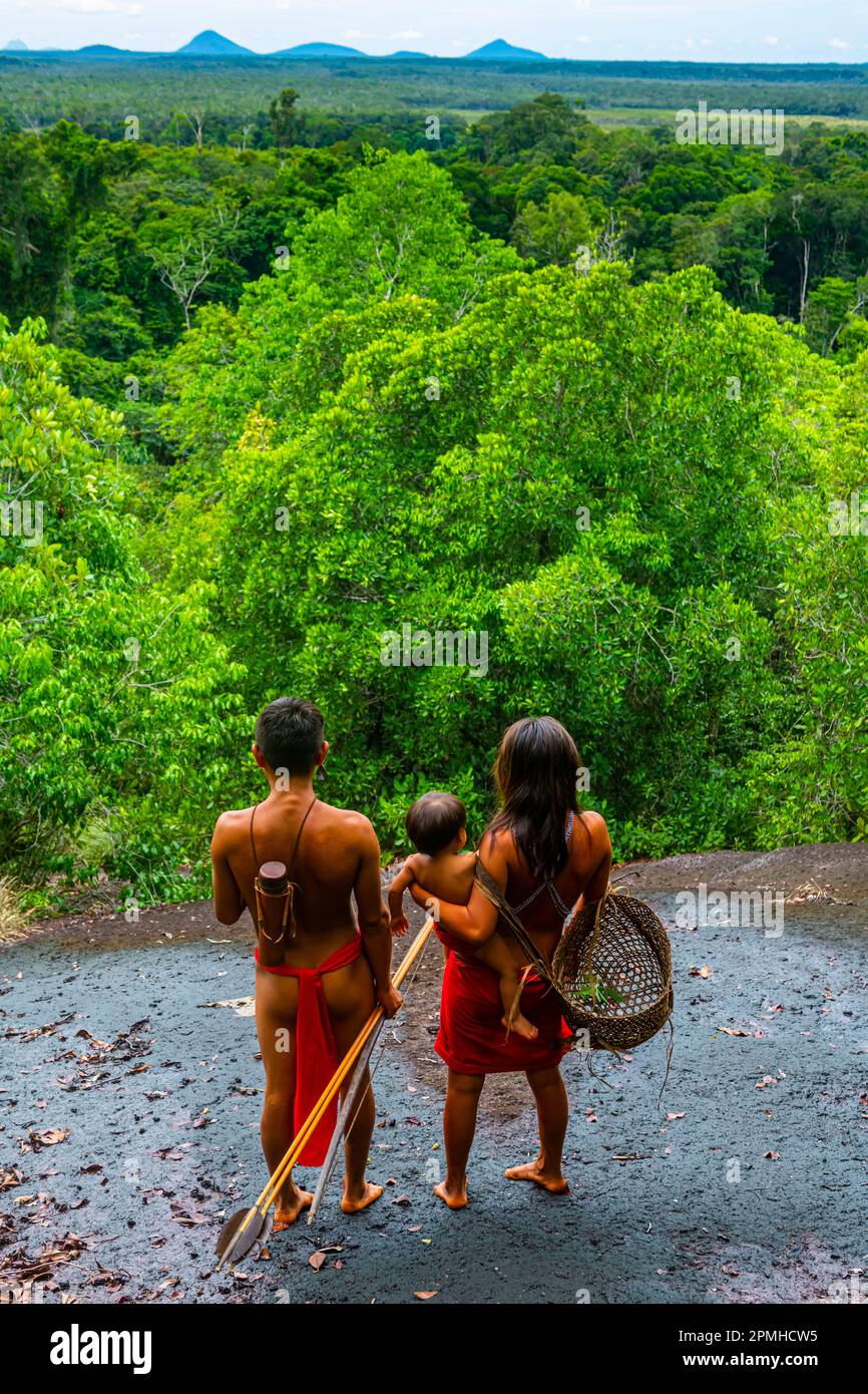 Ein Paar mit ihrem Kind, das auf einem riesigen Felsen steht, dem Yanomami-Stamm, Süd-Venezuela, Südamerika Stockfoto
