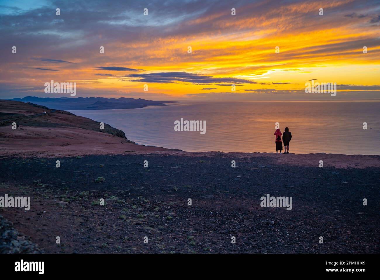 Blick auf ein Paar mit Blick auf die vulkanische Küste von Mirador del Rio bei Sonnenuntergang, Lanzarote, Las Palmas, Kanarische Inseln, Spanien, Atlantik, Europa Stockfoto
