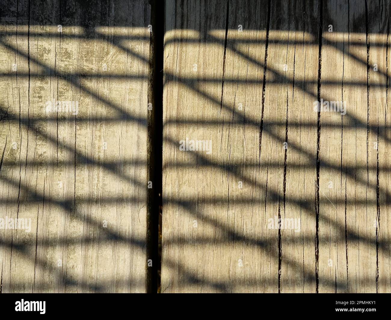 Nahaufnahme des Gitterzaunschattenmusters auf braunem verwittertem Holz Stockfoto
