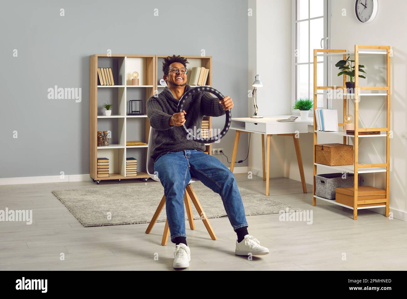 Junger, fröhlicher, lächelnder indianer, der das Lenkrad zu Hause auf einem Stuhl sitzt. Stockfoto
