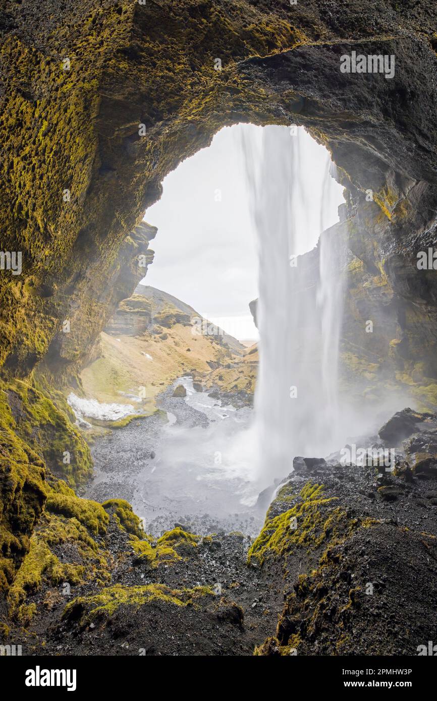 Kvernufoss Wasserfall auf dem Fluss Kverna, von innen gesehen von einer kleinen Höhle hinter dem rauschenden Wasser im Winter, Skógar, Rangárþing Eystra, Süd-Island Stockfoto