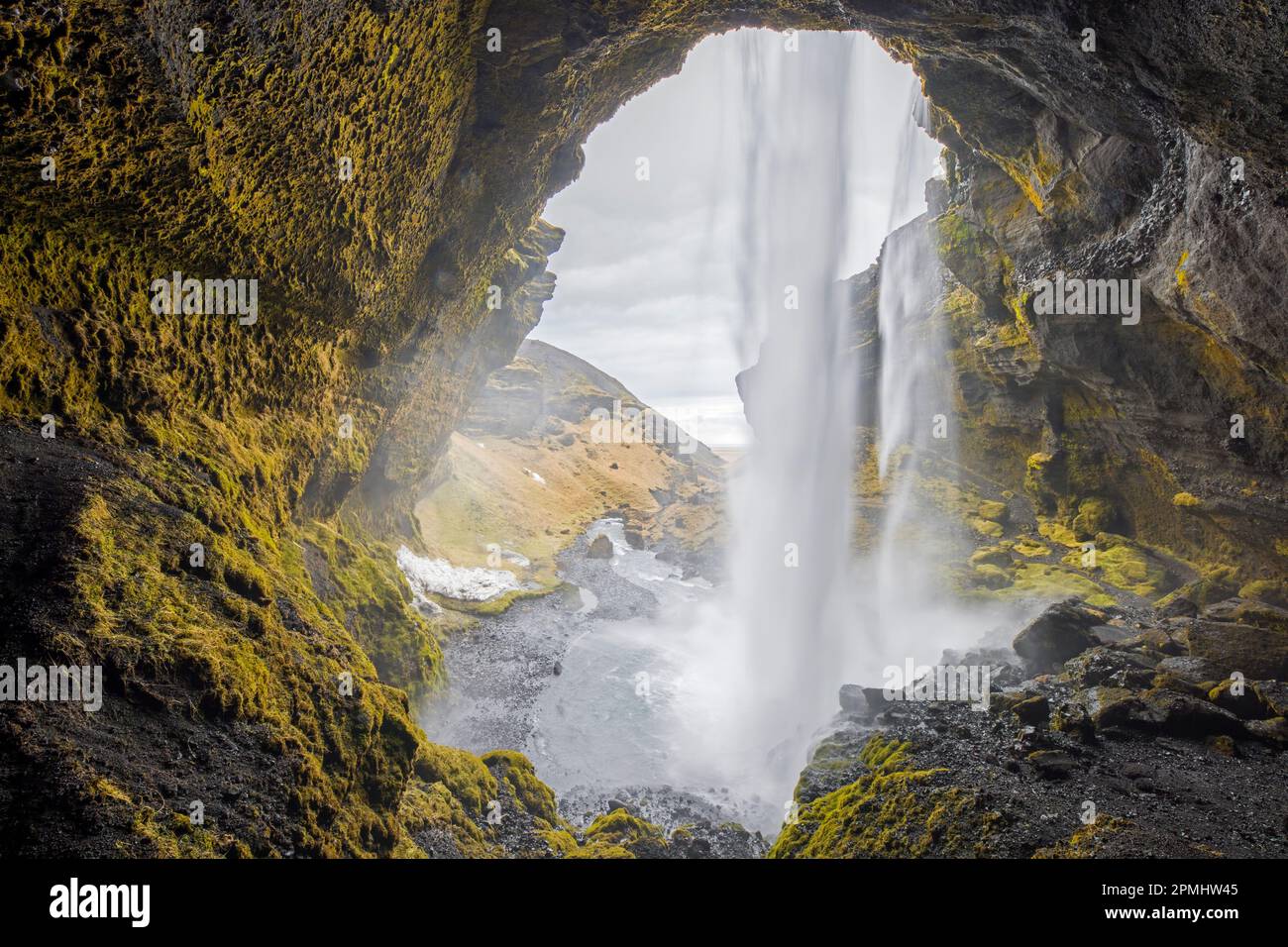 Kvernufoss Wasserfall auf dem Fluss Kverna, von innen gesehen von einer kleinen Höhle hinter dem rauschenden Wasser im Winter, Skógar, Rangárþing Eystra, Süd-Island Stockfoto