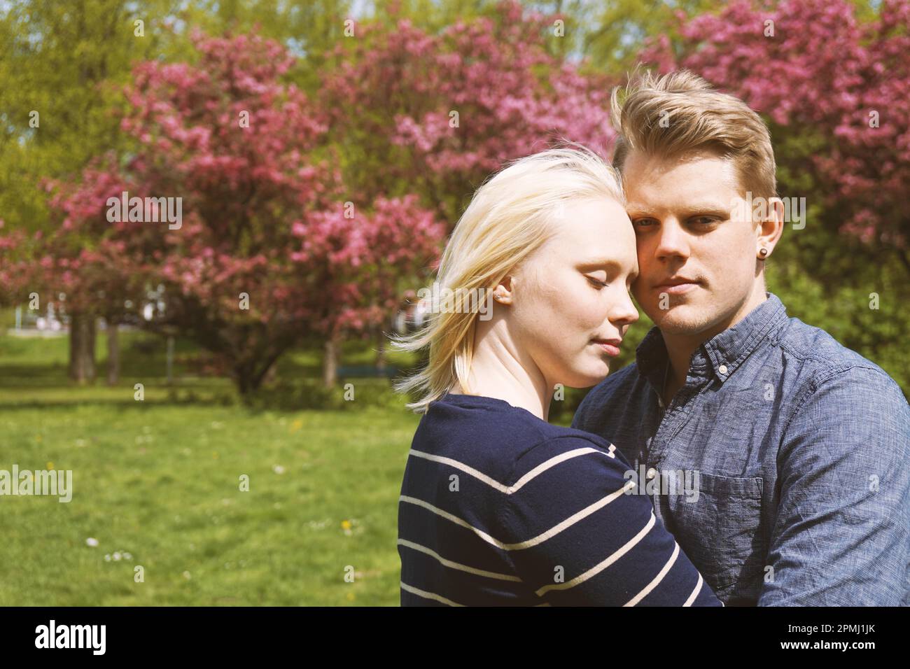 Junges Paar in der Liebe umarmt in der Natur während Kirschblüte im Park Stockfoto