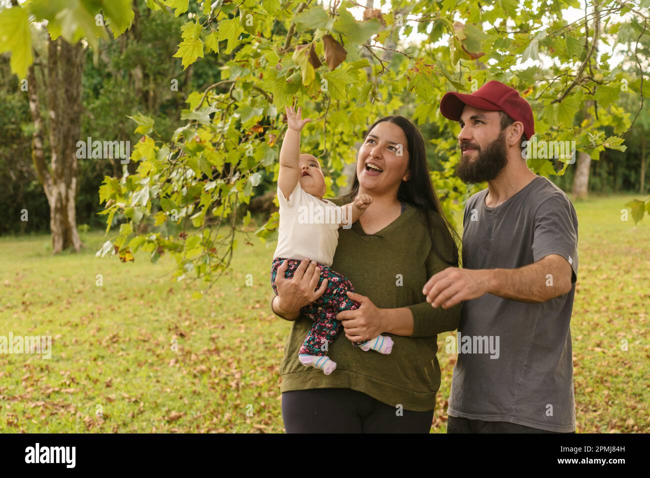 Stolze und glückliche Eltern, die einen Moment mit ihrer Tochter in einer natürlichen Umgebung verbringen. Positive und liebevolle Familie. Stockfoto