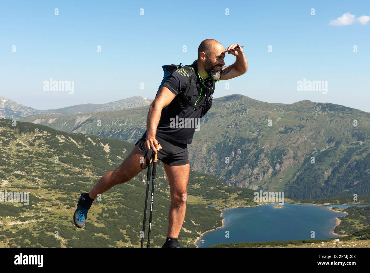 Männlicher Wanderer posiert für ein Foto am Kyoravitsa Peak um 2612m Uhr mit Blick auf den Stinky Lake im Rila-Nationalpark und Naturschutzgebiet, Bulgarien, Balkan Stockfoto