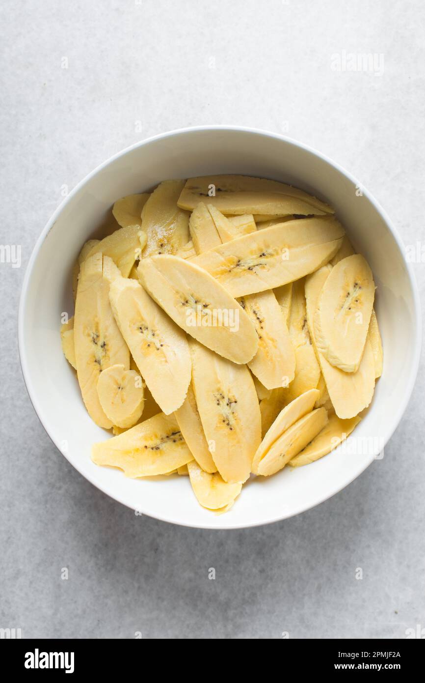 Scheiben reifer Mehlbananen in einer weißen Schüssel, Scheiben gelber Mehlbananen zum Braten, Verfahren zur Herstellung gebratener Mehlbananen Stockfoto