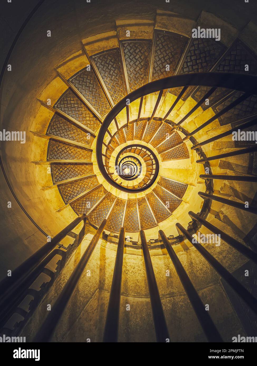Wendeltreppe abstrakte Perspektive mit Blick von unten auf unendliche wirbelnde Treppen in leuchtendem gelben Licht Stockfoto