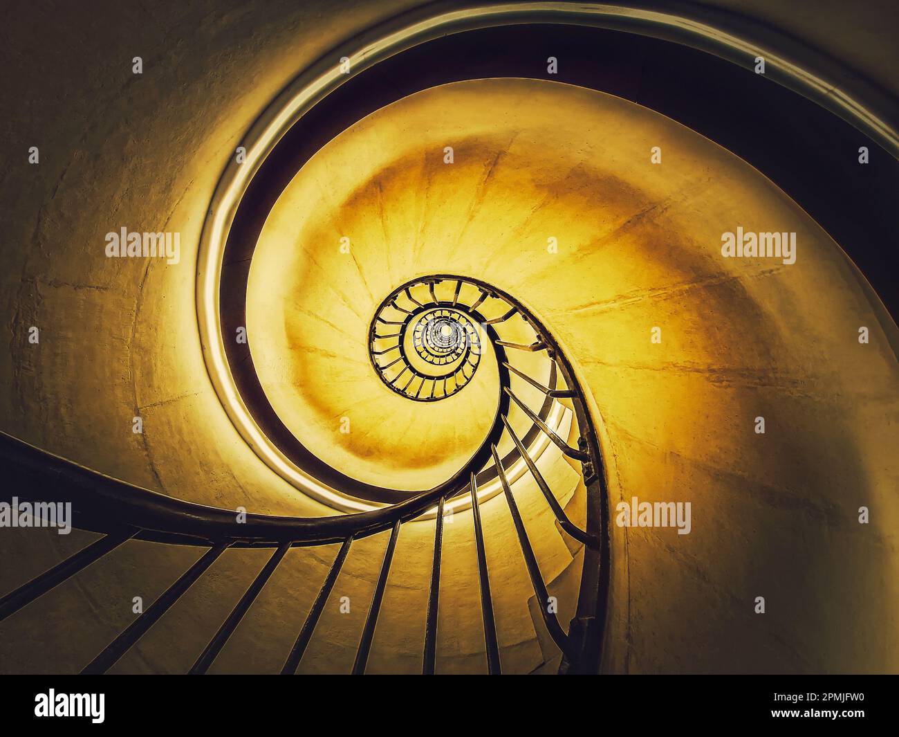 Spiraltreppe abstrakt wirbelnde hypnotisierende Perspektive. Blick von unten auf unendlich kreisförmige Treppen, die im gelben hellen Hintergrund leuchten Stockfoto