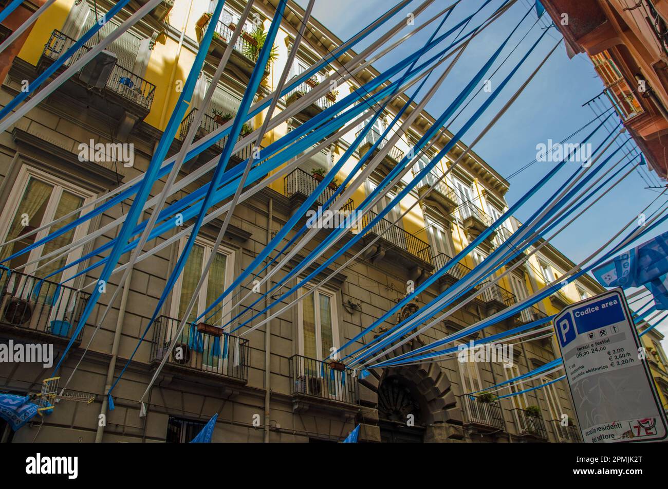 Schauen Sie durch blau-weiße Fahnen, Flaggen und Luftschlangen im historischen Stadtzentrum von Neapel hinauf, während die Bewohner den Erfolg von S.S.C. feiern Stockfoto