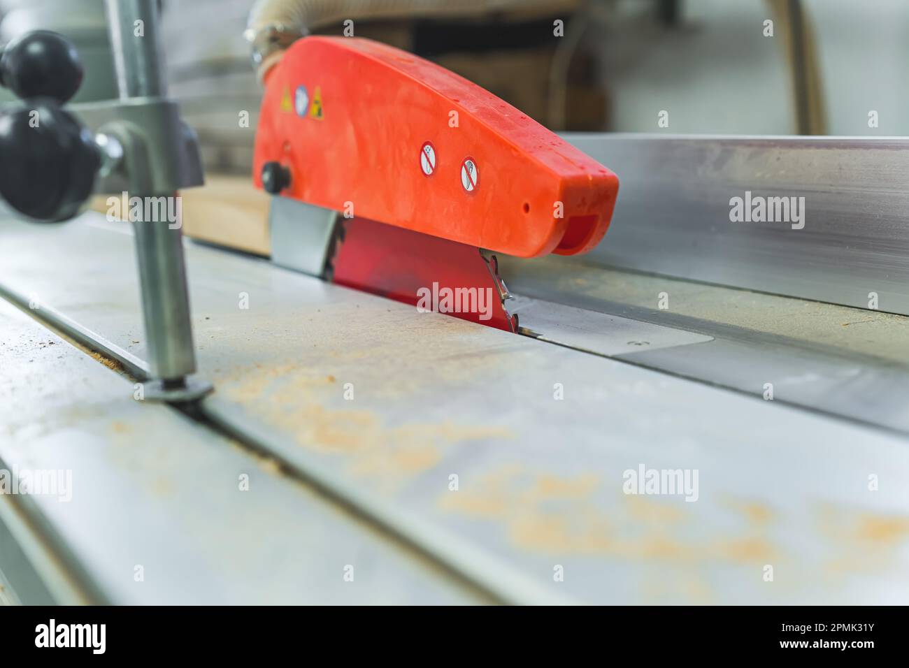 Nahaufnahme des Tischsägeblatts und des orangefarbenen Klingenschutzes. Elektrische Holzbearbeitungswerkzeuge in der Zimmermannswerkstatt. Hochwertiges Foto Stockfoto