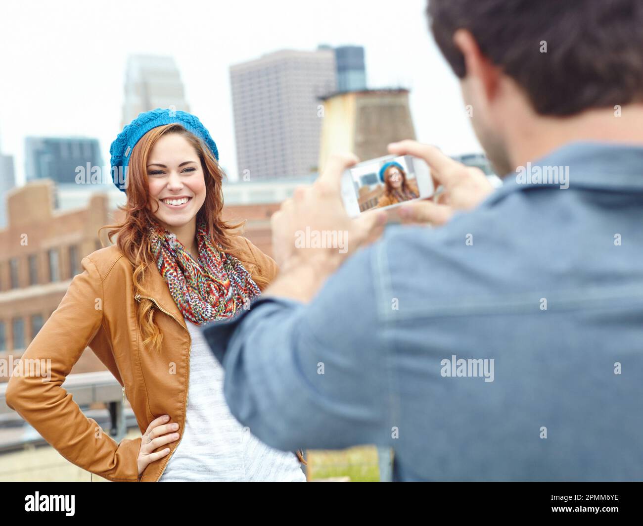Lächeln. Eine attraktive junge Frau posiert, während ihr Freund ein Foto macht. Stockfoto