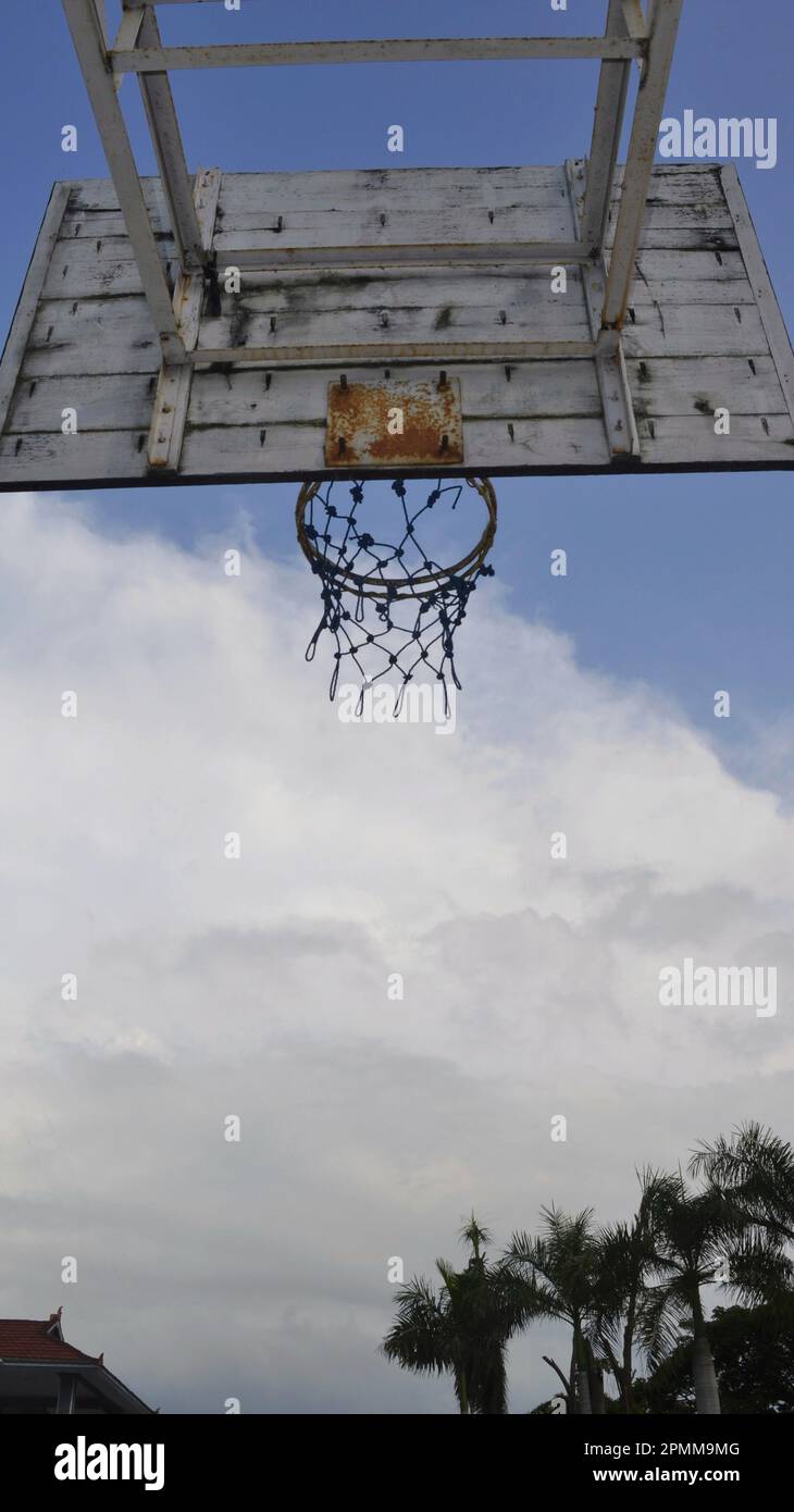 Basketballring von hinten mit blauem Himmel und Bäumen als Hintergrund. Basketballfeld im Freien. Stockfoto