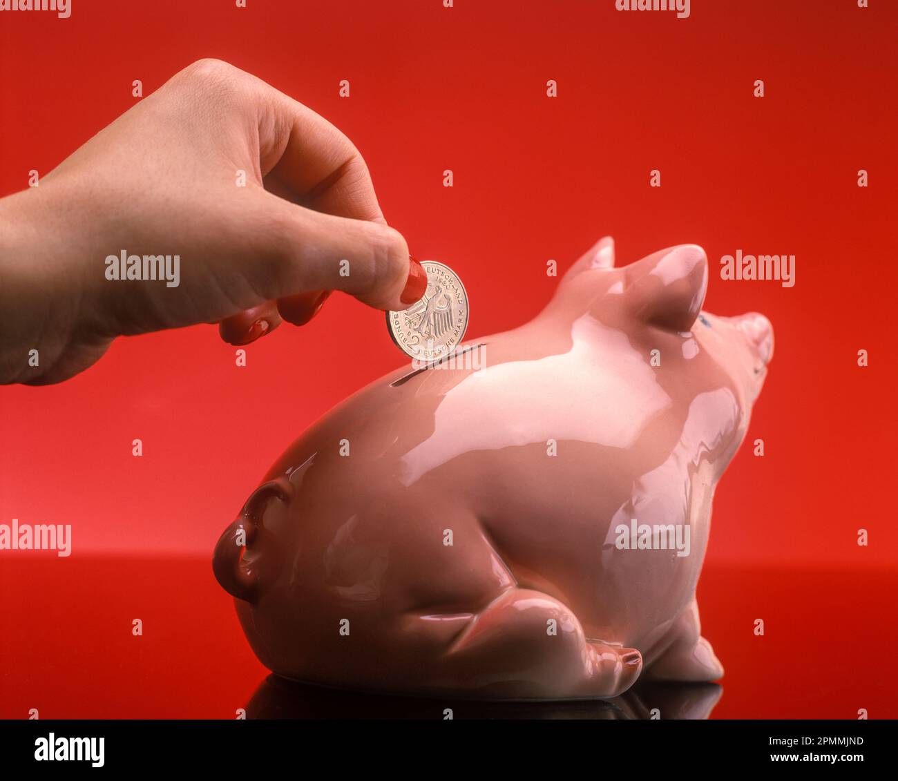1991 HISTORISCHE FRAUEN LEGEN 2 DEUTSCHE-MARK-MÜNZE IN DIE PIGGY BANK Stockfoto