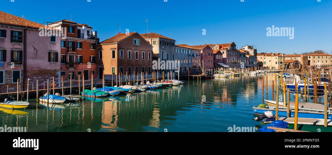 Farbenfrohe Gebäude und Boote legen entlang des Canale de San Pietro im Viertel Castello von Venedig an; Veneto, Venedig, Italien Stockfoto