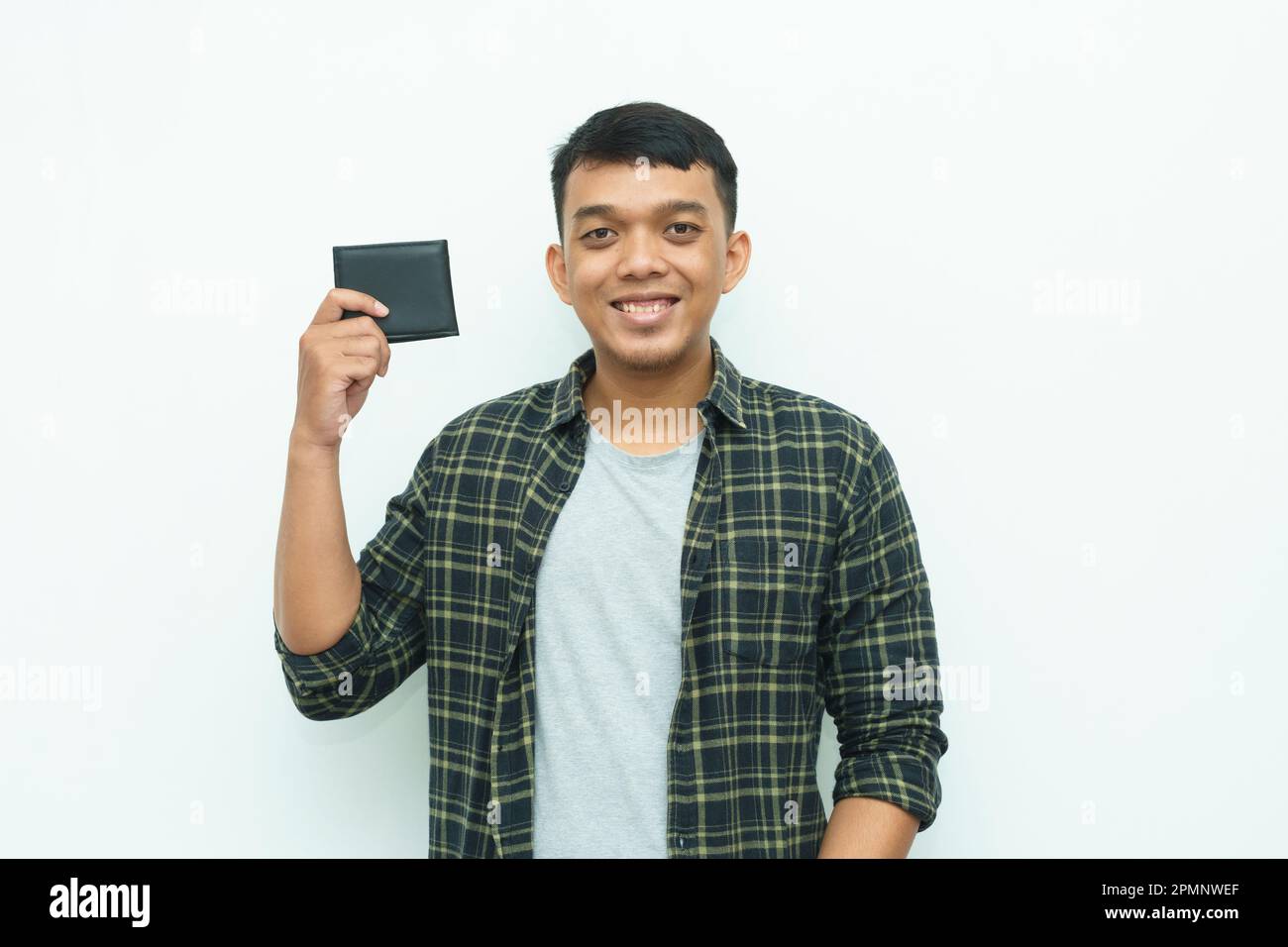 Ein junger asiatischer Mann lächelt, während er die schwarze Brieftasche in der Hand hält Stockfoto