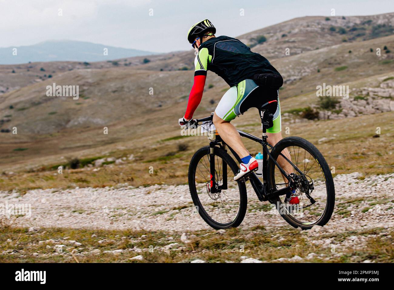 Männlicher Mountainbiker, der im Skilanglaufrennen auf bergigem Gelände sportlich fährt Stockfoto