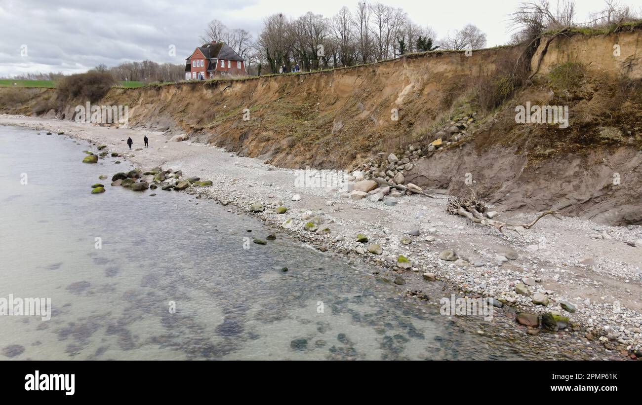 PRODUKTION - 13. April 2023, Schleswig-Holstein, Travemünde: Fußgänger gehen entlang der Brodtener Steilufer. (Luftfoto mit Drohne) der Rand des Brodtener Steilbeines nähert sich unaufhaltsam dem Haus „Seeblick“ der Jugendorganisation „Sozialistische Jugend Deutschlands – die Falken“. (Zu dpa: Abrisskante rückt näher - Haus Seeblick steht fest über der Ostsee) Foto: Frank Molter/dpa Stockfoto