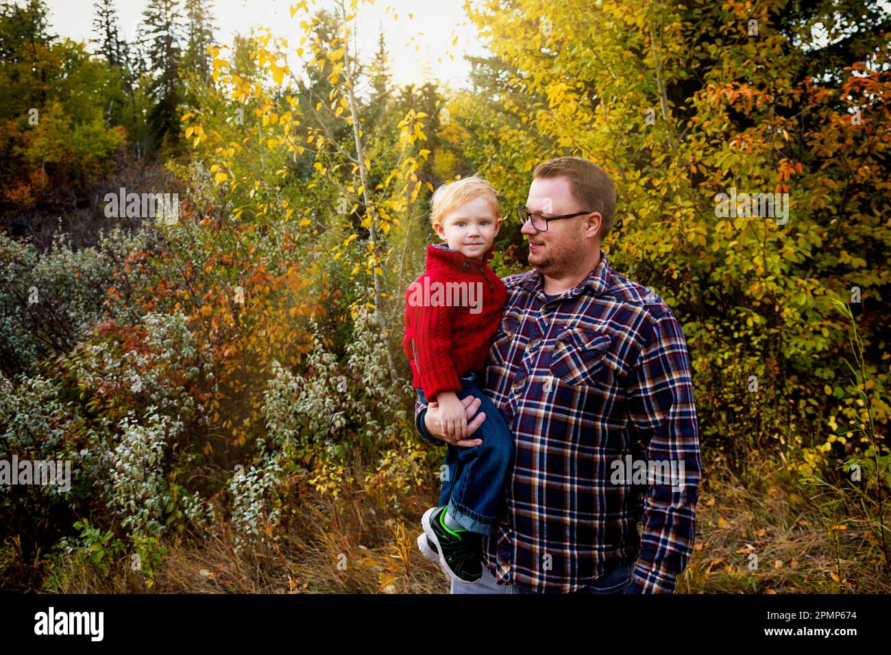 Porträt eines Vaters mit seinem jungen Sohn im Herbst in einem Park in Edmonton, Alberta, Kanada Stockfoto