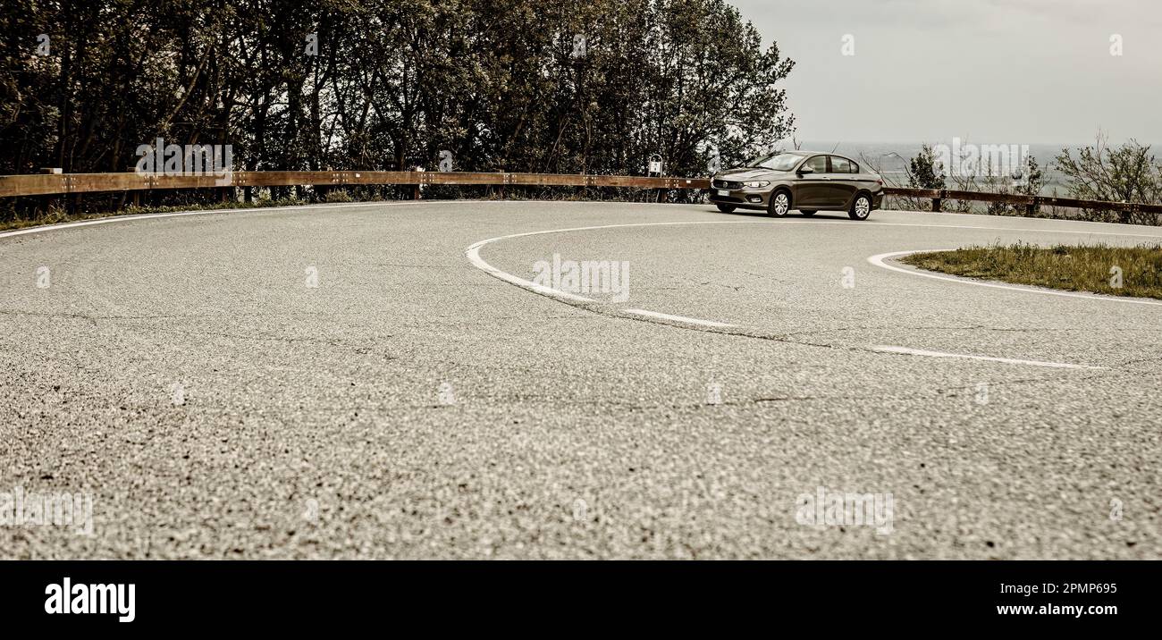 Dynamische Aufnahme eines Autos, das eine kurvige Bergstraße mit Haarnadelkurven hinauffährt. Stockfoto