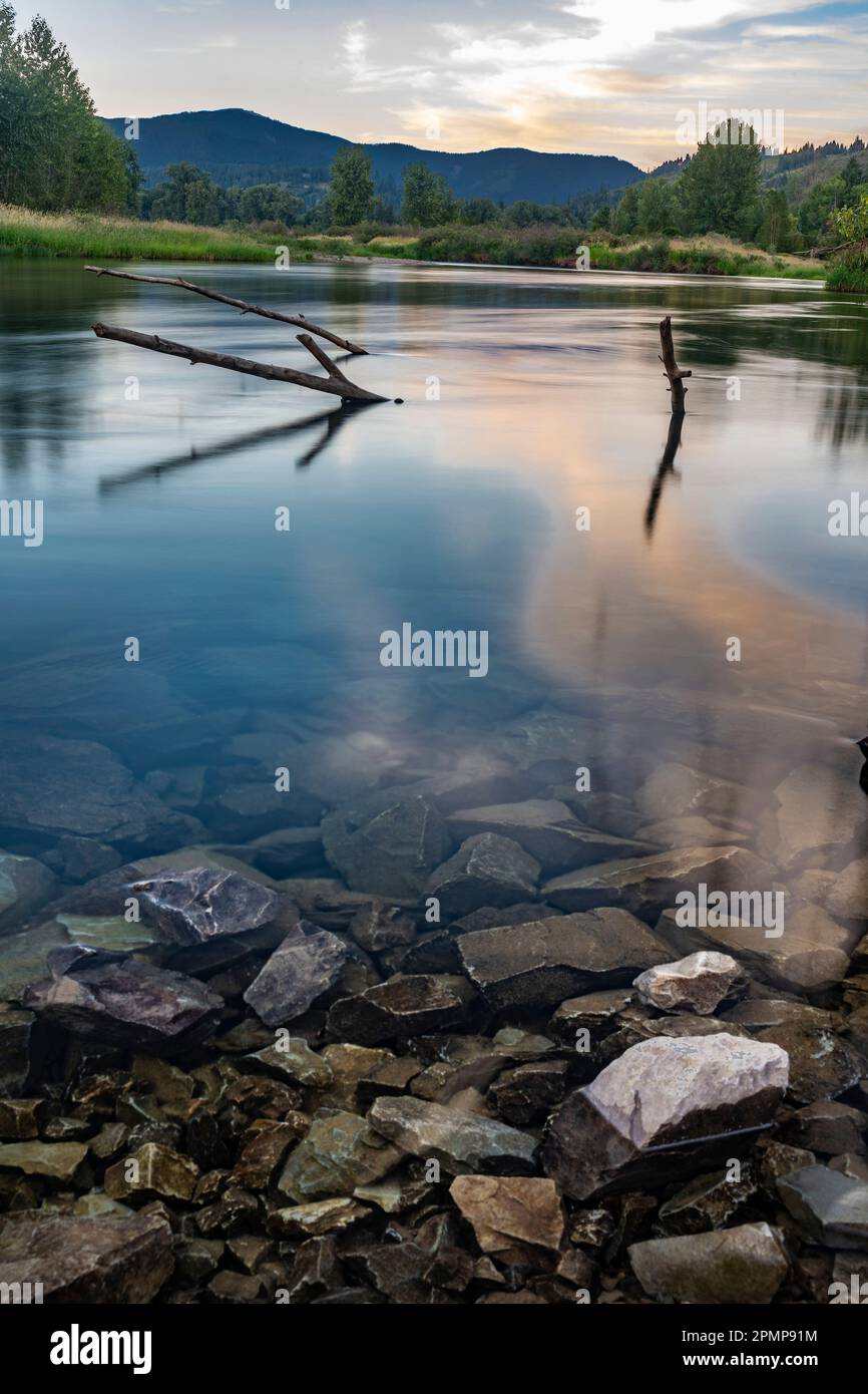 Rosey-Sonnenuntergangswolken im klaren, glatten Wasser des Coeur d'Alene River bei Kingston, Idaho, USA Stockfoto