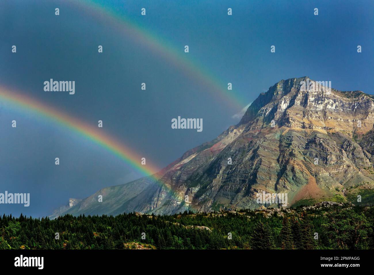 Doppelter Regenbogen mit Bergen und dunkelblauem Himmel im Waterton Lakes National Park in Waterton, Alberta, Kanada Stockfoto