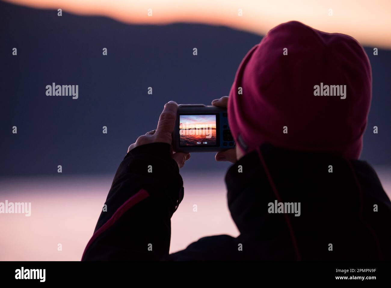 Bei Sonnenaufgang fängt eine Person mit einer Kamera den Moment auf der Inside Passage, Inside Passage, British Columbia, Kanada, ein Stockfoto