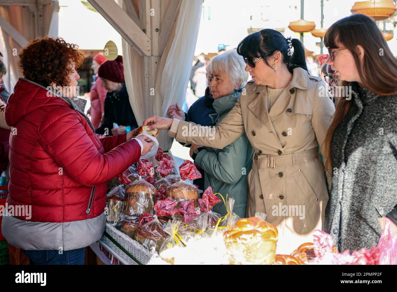 IVANO-FRANKIVSK, UKRAINE - 13. APRIL 2023 - Ein Verkäufer bietet an, während einer Ostermesse am Rynok Square, Ivano-Fra, Pasks (ukrainisches Osterbrot) zu probieren Stockfoto