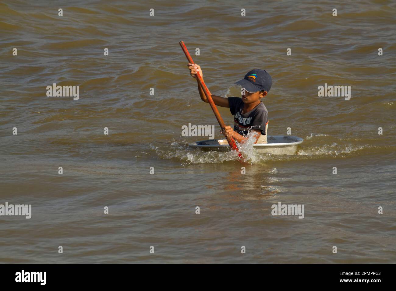 Kind navigiert auf einem Boot auf dem „Great Lake“ oder Tonle SAP; Tonle SAP, Kambodscha Stockfoto