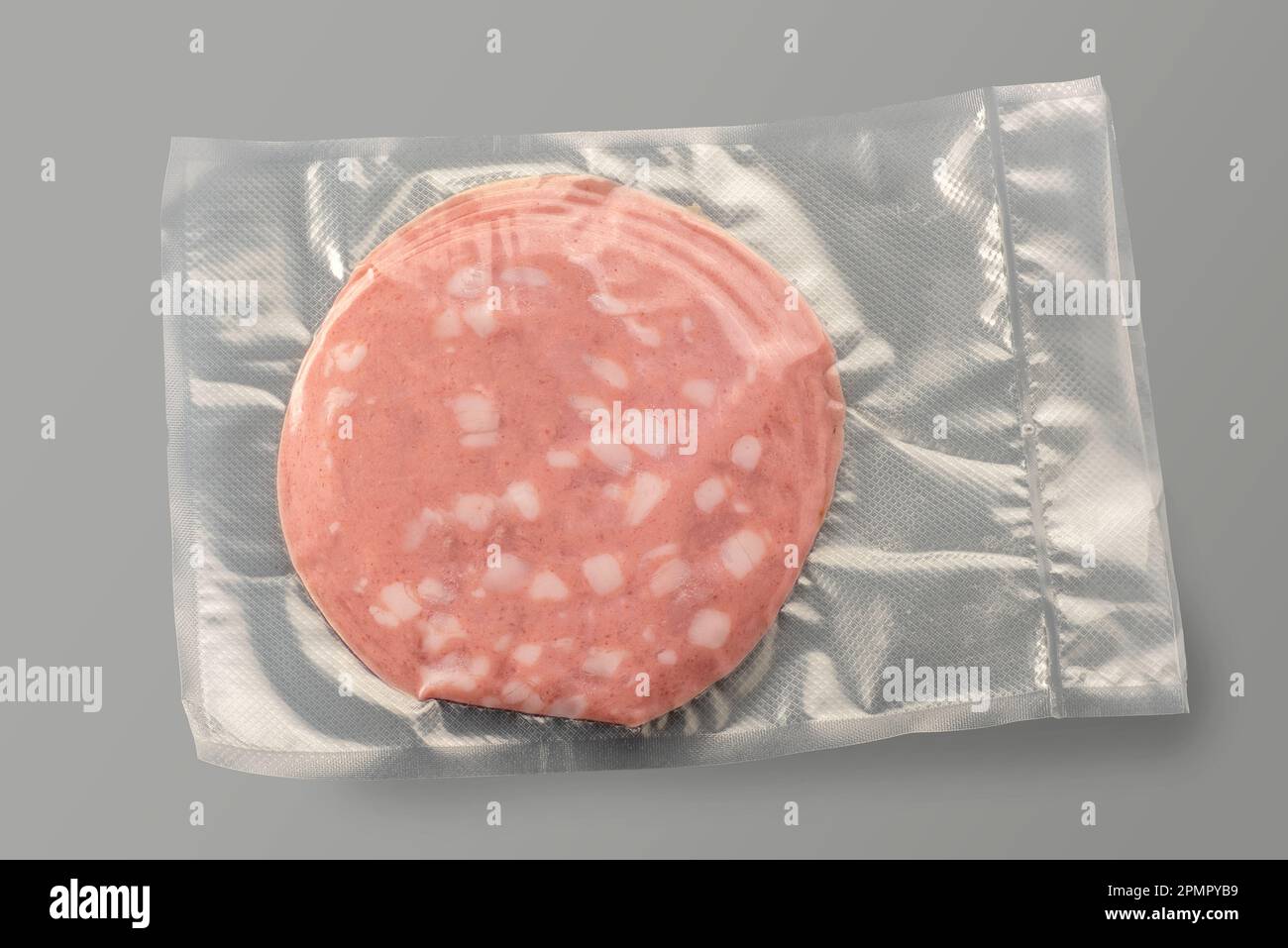 Scheiben von Mortadella in vakuumversiegelter Verpackung zum Kochen von Sous Vide isoliert auf Grau Stockfoto