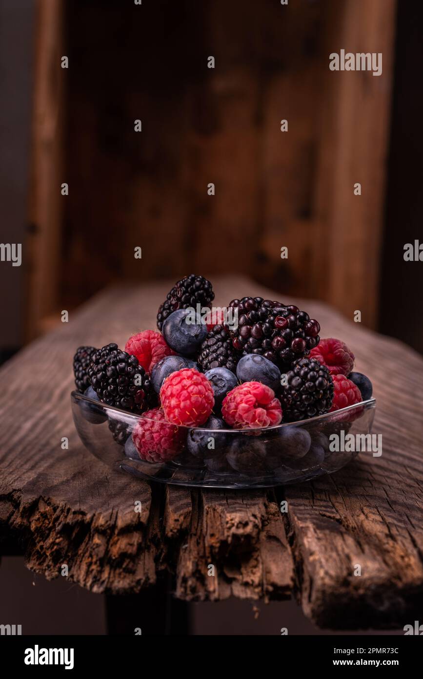 Verschiedene Beeren auf einer Glasplatte. Rote Beeren auf einem Holztisch. Schöne Zusammensetzung von Beeren. Vertikaler Rahmen. Stockfoto