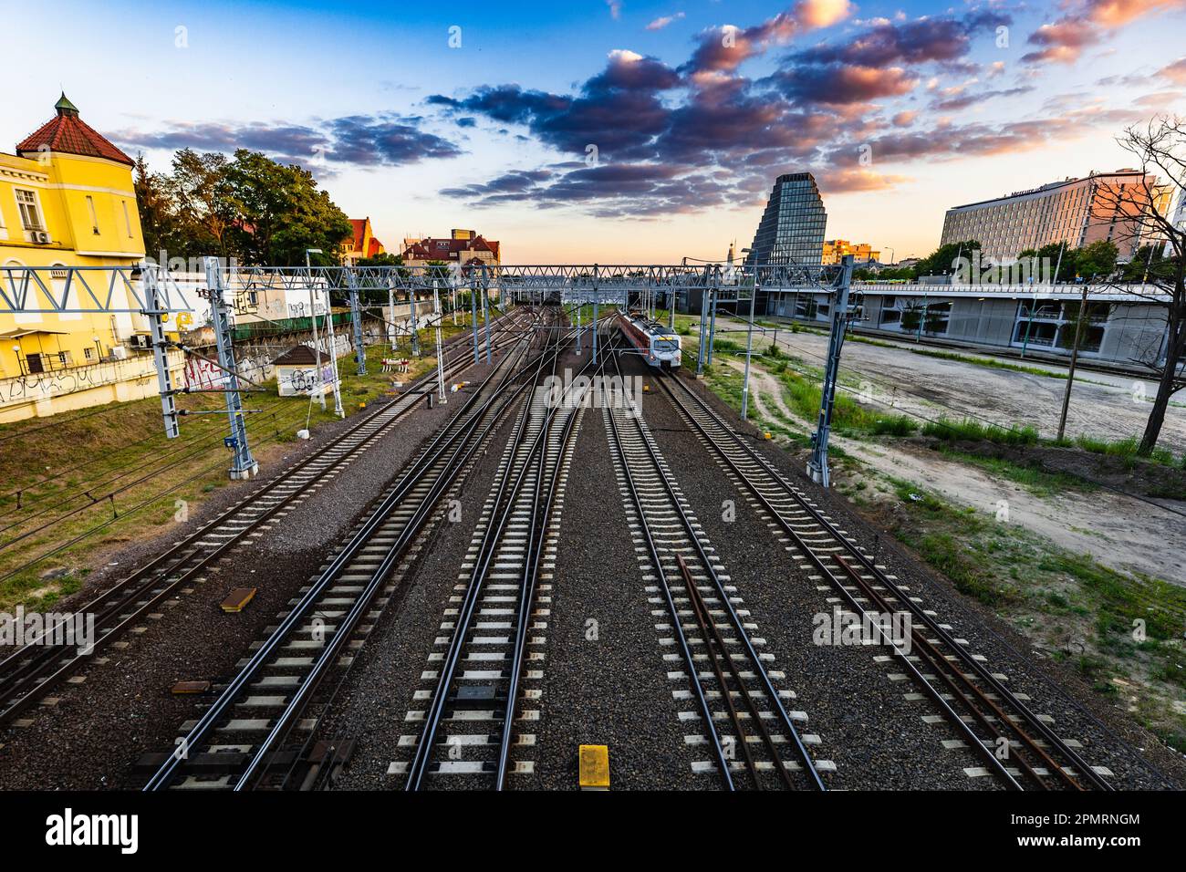 Poznan, Polen - Juli 2022: Der Blick von der Teatralny-Brücke auf den Bahngleisen, beweglichen Zügen und die Skyline der Stadt bei Sonnenuntergang Stockfoto