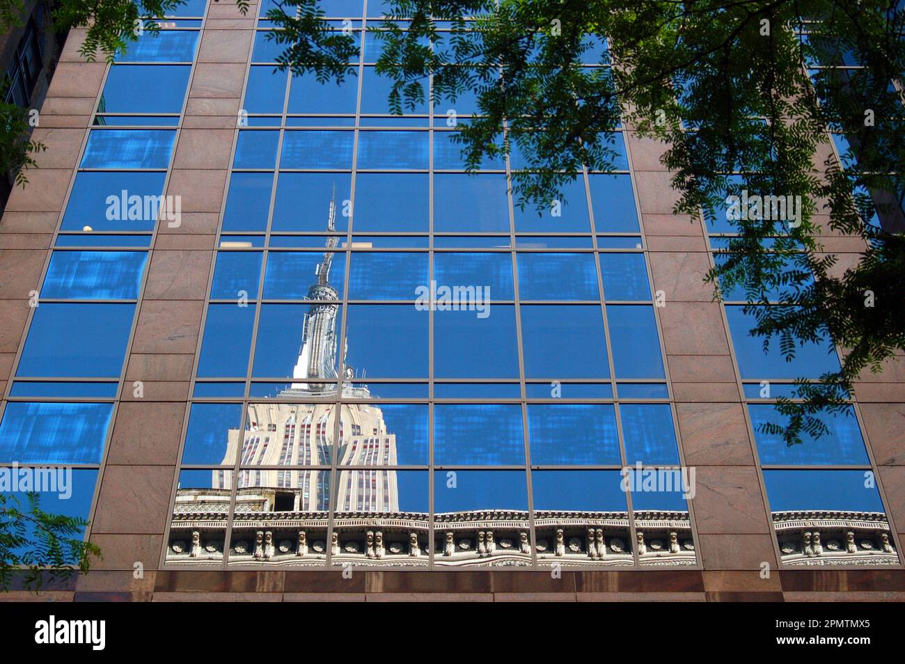 Das Empire State Building spiegelt sich in den Fenstern der umliegenden Gebäude von New York City wider Stockfoto