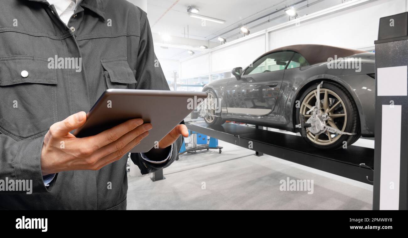 Servicemitarbeiter mit digitalem Tablet auf dem Hintergrund des Fahrzeugs beim Autoservice. Hochwertiges Foto Stockfoto