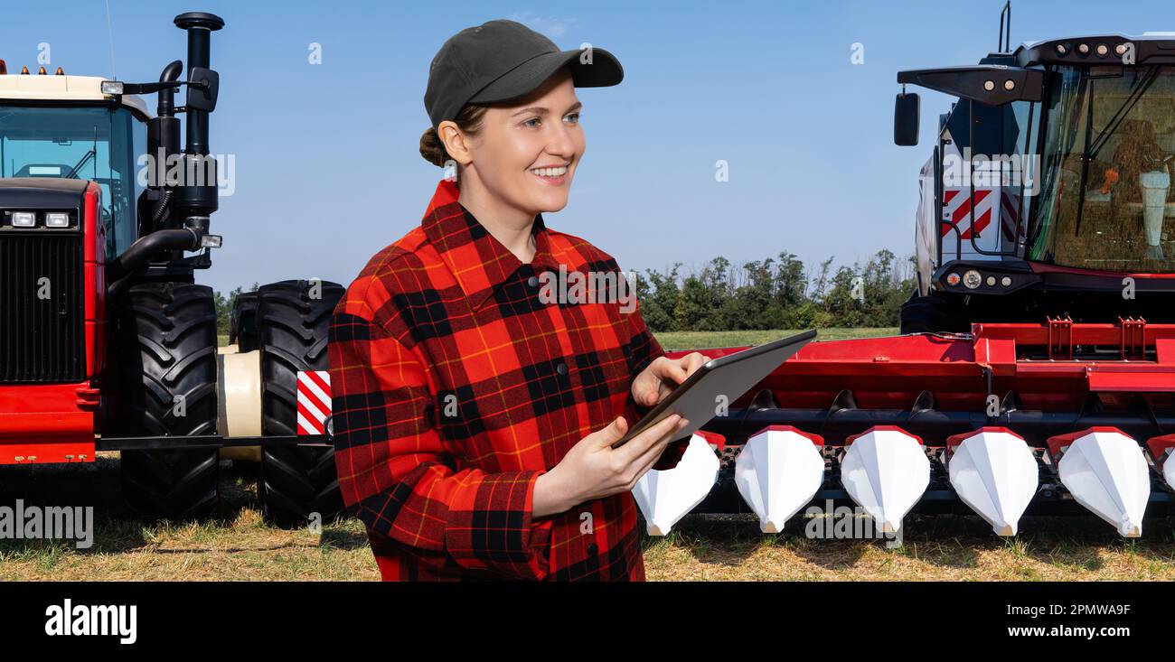 Landwirt mit digitalem Tablet auf dem Hintergrund von Mähdrescher und Traktor. Konzept der intelligenten Landwirtschaft. Hochwertiges Foto Stockfoto