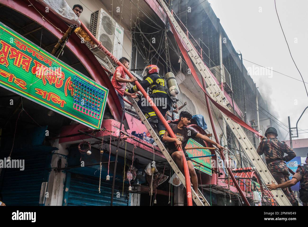 Dhaka, Bangladesch. 15. April 2023. Die drei uniformierten Militärdienste des Landes, Armee, Marine, Luftwaffe und das Schnelleinsatzbataillon helfen, ein Feuer im New Supermarket in Dhaka zu löschen. In Dhakas neuem Supermarkt, einem der größten Bekleidungsmärkte des Landes, vor Eid-ul-Fitr, hat ein massives Feuer die Geschäfte ausgelöscht. Einsatzkräfte der Armee, der Luftwaffe, des Schnelleinsatzbataillons, der Polizei von Bangladesch und des Grenzschutzes Bangladesch haben sich mit 28 Feuerwehr- und Zivilschutzeinheiten zusammengetan, um am Samstag die Flammen zu zähmen. Kredit: SOPA Images Limited/Alamy Live News Stockfoto