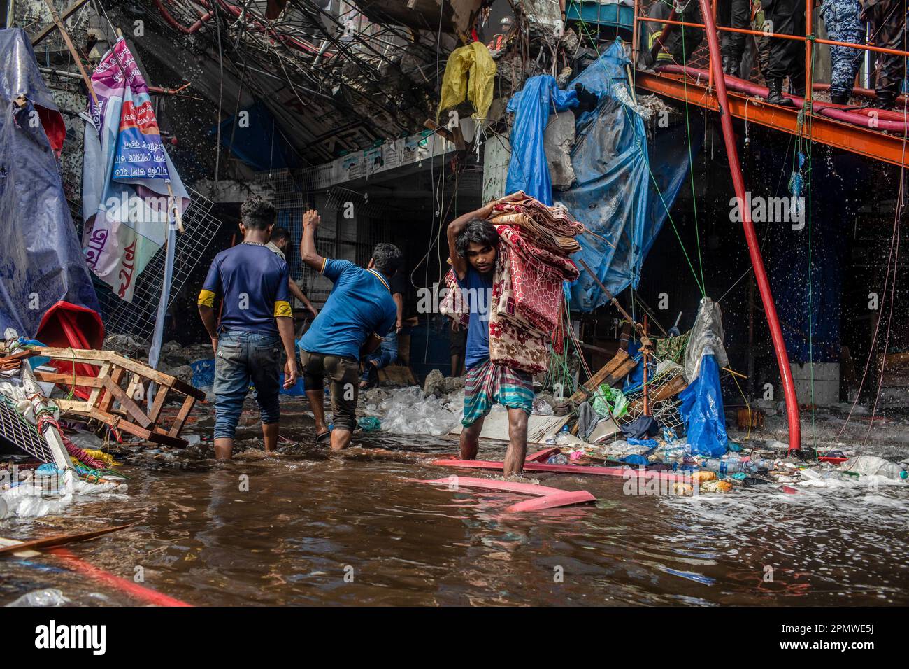 Dhaka, Bangladesch. 15. April 2023. Unternehmenseigentümer bringen ihre Waren vom Brandort im neuen Supermarkt in Dhaka. In Dhakas neuem Supermarkt, einem der größten Bekleidungsmärkte des Landes, vor Eid-ul-Fitr, hat ein massives Feuer die Geschäfte ausgelöscht. Einsatzkräfte der Armee, der Luftwaffe, des Schnelleinsatzbataillons, der Polizei von Bangladesch und des Grenzschutzes Bangladesch haben sich mit 28 Feuerwehr- und Zivilschutzeinheiten zusammengetan, um am Samstag die Flammen zu zähmen. Kredit: SOPA Images Limited/Alamy Live News Stockfoto