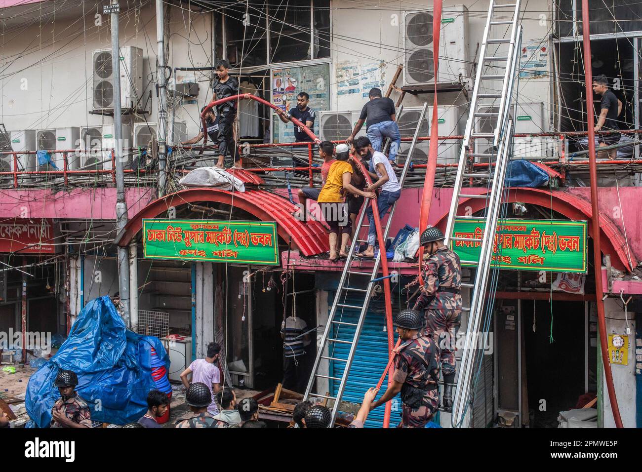 Dhaka, Bangladesch. 15. April 2023. Die drei uniformierten Militärdienste des Landes, Armee, Marine, Luftwaffe und das Schnelleinsatzbataillon helfen, ein Feuer im New Supermarket in Dhaka zu löschen. In Dhakas neuem Supermarkt, einem der größten Bekleidungsmärkte des Landes, vor Eid-ul-Fitr, hat ein massives Feuer die Geschäfte ausgelöscht. Einsatzkräfte der Armee, der Luftwaffe, des Schnelleinsatzbataillons, der Polizei von Bangladesch und des Grenzschutzes Bangladesch haben sich mit 28 Feuerwehr- und Zivilschutzeinheiten zusammengetan, um am Samstag die Flammen zu zähmen. Kredit: SOPA Images Limited/Alamy Live News Stockfoto