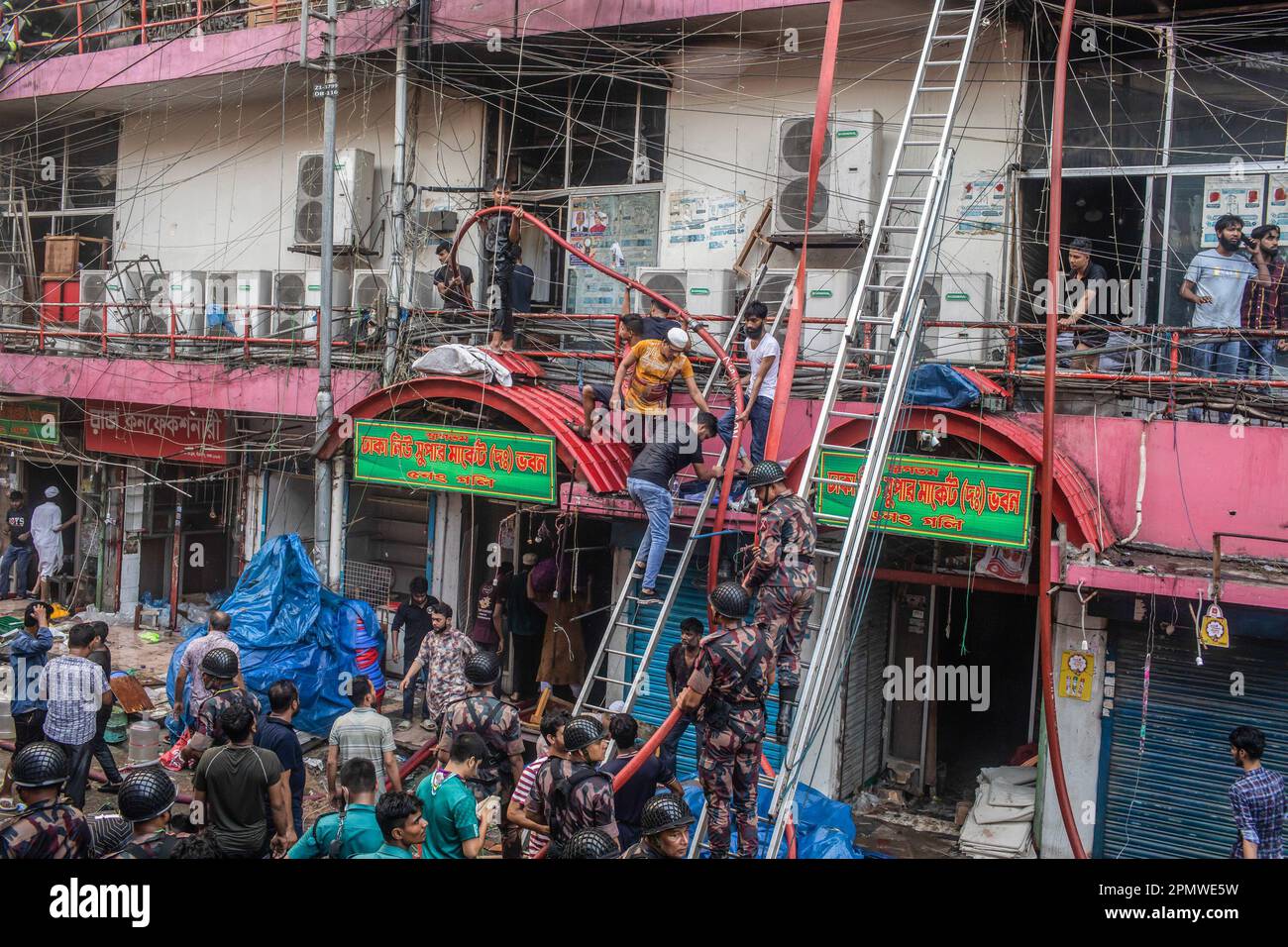 Dhaka, Bangladesch. 15. April 2023. Die drei uniformierten Militärdienste des Landes, Armee, Marine, Luftwaffe und das Schnelleinsatzbataillon helfen, ein Feuer im New Supermarket in Dhaka zu löschen. In Dhakas neuem Supermarkt, einem der größten Bekleidungsmärkte des Landes, vor Eid-ul-Fitr, hat ein massives Feuer die Geschäfte ausgelöscht. Einsatzkräfte der Armee, der Luftwaffe, des Schnelleinsatzbataillons, der Polizei von Bangladesch und des Grenzschutzes Bangladesch haben sich mit 28 Feuerwehr- und Zivilschutzeinheiten zusammengetan, um am Samstag die Flammen zu zähmen. Kredit: SOPA Images Limited/Alamy Live News Stockfoto