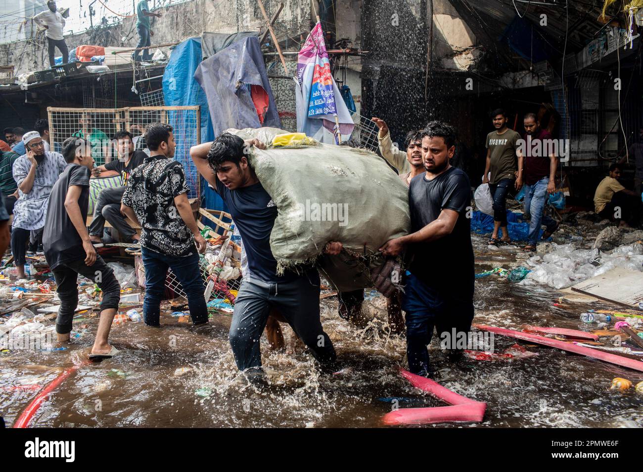 Dhaka, Bangladesch. 15. April 2023. Unternehmenseigentümer bringen ihre Waren vom Brandort im neuen Supermarkt in Dhaka. In Dhakas neuem Supermarkt, einem der größten Bekleidungsmärkte des Landes, vor Eid-ul-Fitr, hat ein massives Feuer die Geschäfte ausgelöscht. Einsatzkräfte der Armee, der Luftwaffe, des Schnelleinsatzbataillons, der Polizei von Bangladesch und des Grenzschutzes Bangladesch haben sich mit 28 Feuerwehr- und Zivilschutzeinheiten zusammengetan, um am Samstag die Flammen zu zähmen. Kredit: SOPA Images Limited/Alamy Live News Stockfoto