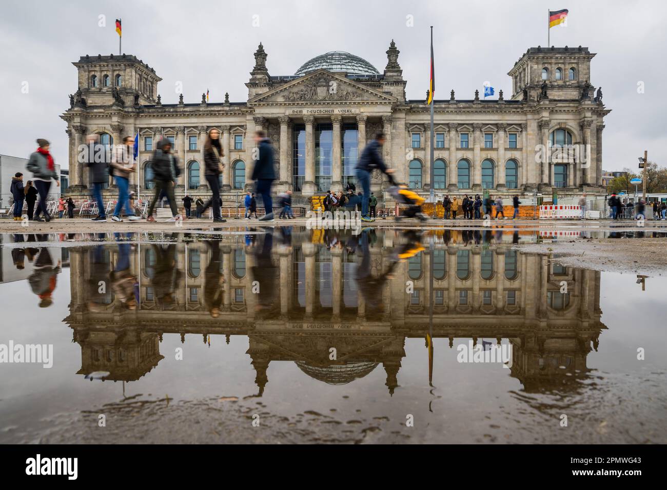 Berlin, Deutschland. 15. April 2023. Vor dem Reichstagsgebäude laufen die Menschen zwischen den Pfützen. Kredit: Christoph Soeder/dpa/Alamy Live News Stockfoto