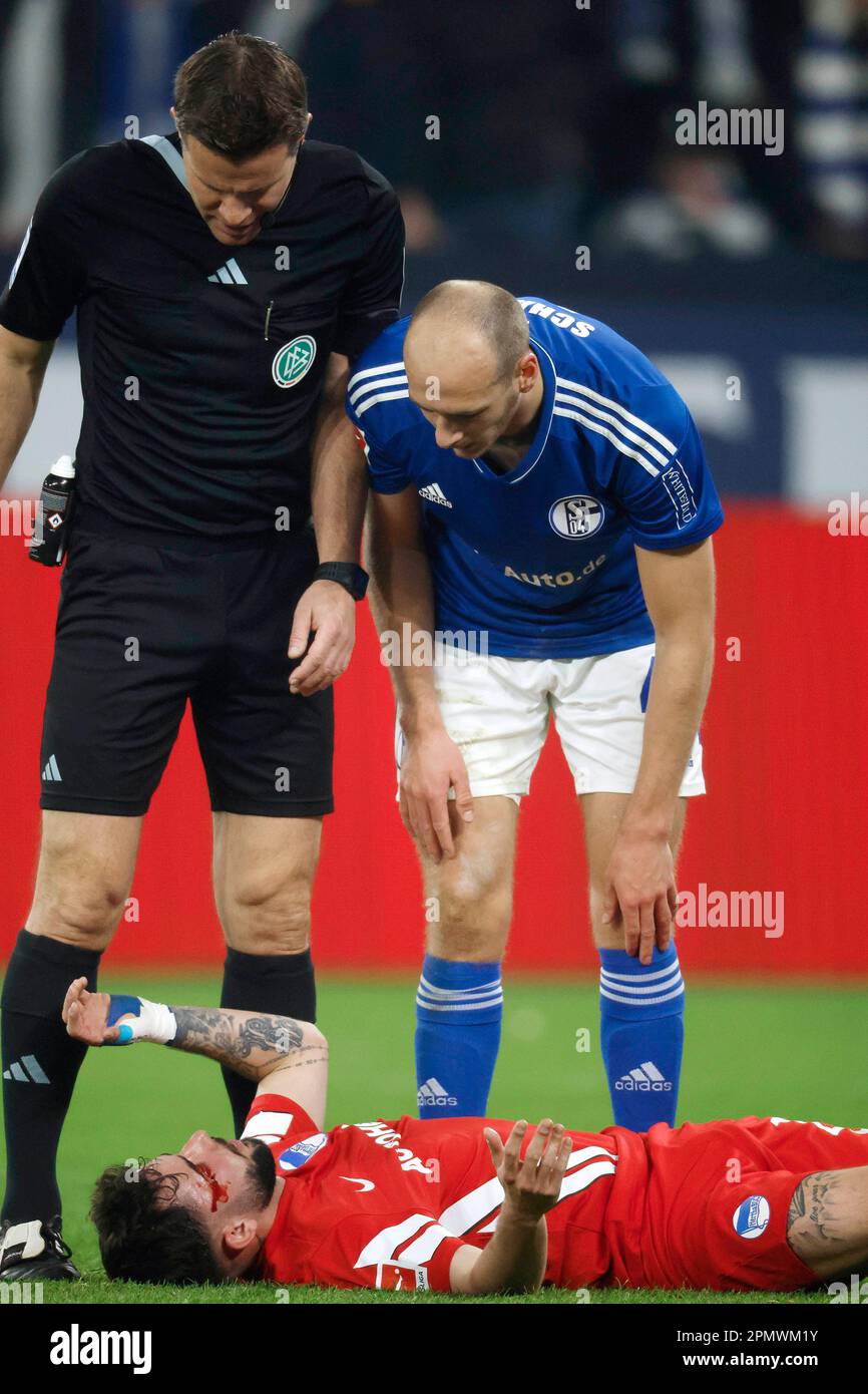Gelsenkirchen, Deutschland, 1. Fussball Bundesliga 28. Spieltag FC Schalke 04 vs.Hertha BSC Berlin 5:2 am 14. 04. 2023 in der Veltins Arena auf Schalke in Gelsenkirchen SR. Felix BRYCH -L- und Henning MATRICIANI (S04) -R- kümmern sich um den am Boden liegenden und verletzten Marco RICHTER (HBSC) Foto: Norbert Schmidt, Düsseldorf Stockfoto
