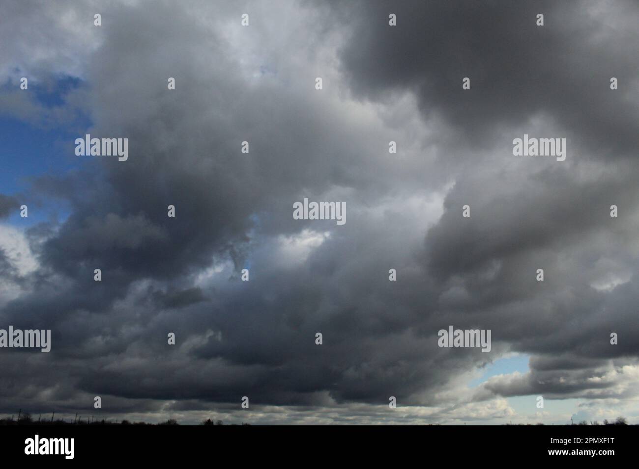 Schwere graue Sturmwolken, die über der Erde hängen Stockfoto