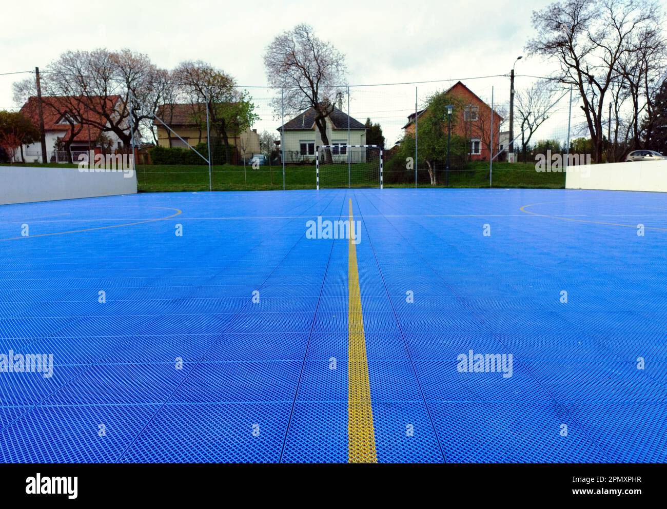 Kleiner Fußballplatz im Freien mit blauem Vinylfußboden. Ineinander greifende Fliesen. Moderne Freizeit- und Gleisböden. Feldteiler mit gelber Farblinie Stockfoto